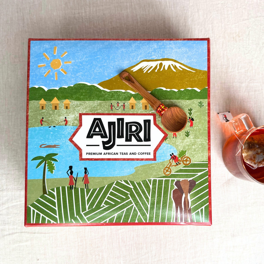 Illustrated Ajiri gift box lid showing Mount Kilimanjaro, with a beaded wooden scoop and a cup of tea