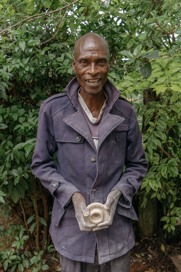 Kisii stone carver holding a newly carved soapstone candle holder