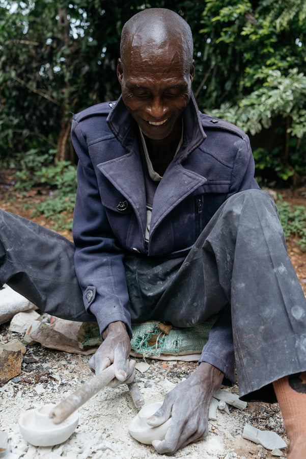 Kisii artisan hand-carving a soapstone candle holder with a chisel