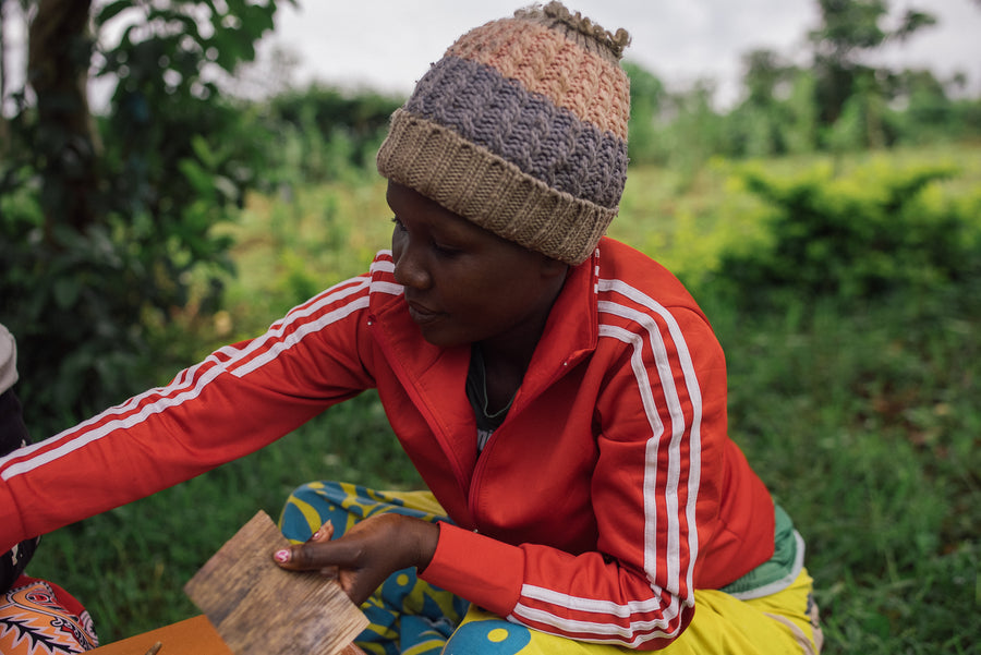 An Ajiri artisan selecting a sheet of dried banana bark to make labels